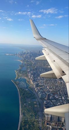 the wing of an airplane flying over a large body of water and cityscape