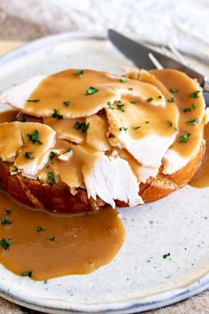 a white plate topped with meat covered in gravy and sauce next to a fork