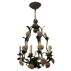 a chandelier with flowers and candles hanging from it