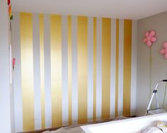 a bathroom with yellow and white striped wallpaper next to a bathtub in the corner