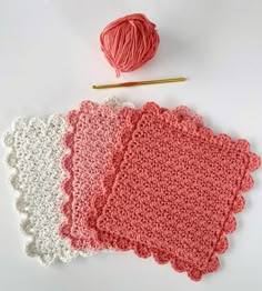 three crocheted placemats with yarn on the top one is pink and white