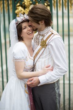 a young man and woman dressed in historical costumes hugging each other outside on the street