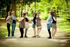 four women are standing in the middle of a road with their arms around each other