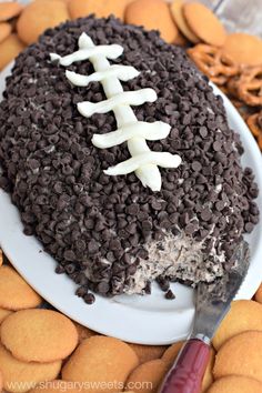 a football cake on a plate with cookies around it