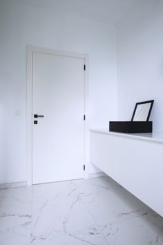 a white room with marble flooring and a black box on the counter next to it