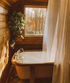 an old fashioned bathtub in a rustic bathroom with wood walls and flooring, along with a curtained window