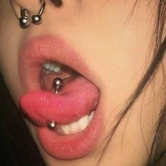 a close up of a person's nose with piercings on it and the tongue sticking out