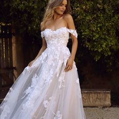 a woman in a white wedding dress posing for the camera with her hand on her hip