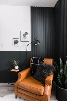 a brown leather chair sitting next to a black and white wall with pictures on it