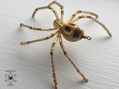 a golden colored spider sitting on top of a white table next to a black and gold skull