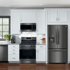 a modern kitchen with stainless steel appliances and white cabinetry, along with hardwood flooring