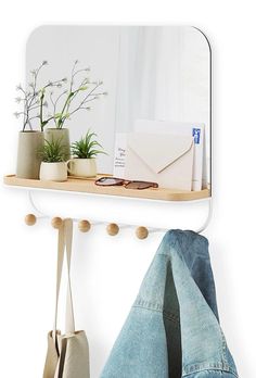 a mirror and coat rack on a white wall next to a pair of blue jeans