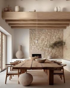 a large wooden table sitting in the middle of a room next to a stone wall