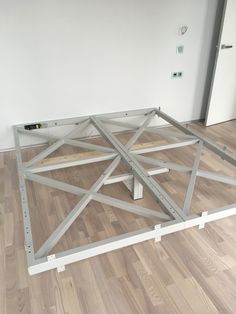 a metal frame on the floor in a room with hard wood floors and white walls