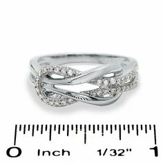 a white gold ring with diamonds on it next to a measuring ruler and tape measure