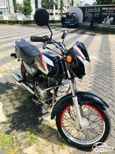 a black and silver motorcycle parked on top of a brick road