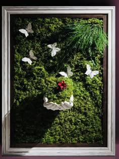 a moss covered wall with white paper butterflies