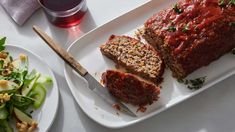 meatloaf and salad on a white plate next to a glass of red wine