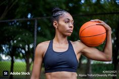 a woman holding a basketball in her right hand and looking at the camera with an intense look on her face