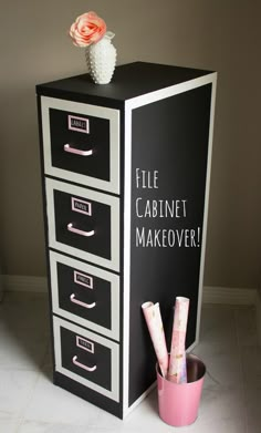 a black and white filing cabinet with pink flowers on top, next to a flower pot