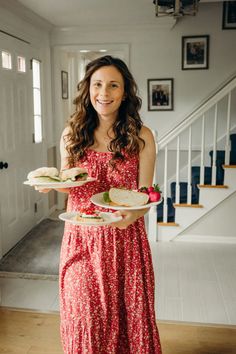 a woman in a red dress holding plates with food on them