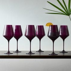 five wine glasses are lined up on a shelf