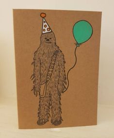 a brown card with a drawing of a bigfoot wearing a party hat and holding a balloon