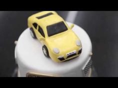 a yellow toy car sitting on top of a white cake