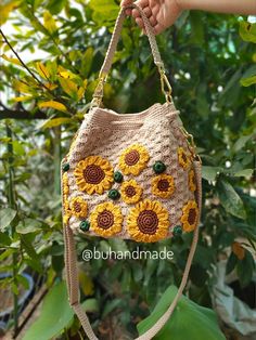 a crocheted bag with sunflowers on it hanging from a tree branch