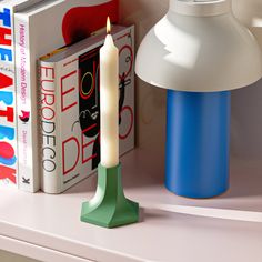 a candle is sitting on a shelf next to some books and a book lamp in the corner