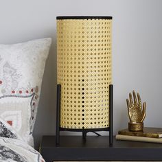 a yellow basket sitting on top of a nightstand next to a pillow