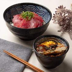 two black bowls filled with food next to chopsticks