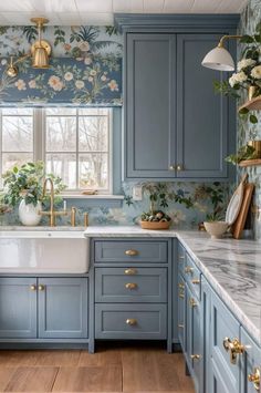 a kitchen with blue cabinets and floral wallpaper on the backsplash, gold faucets