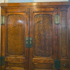 an old wooden armoire with two doors and knobs on the front, sitting against a wall