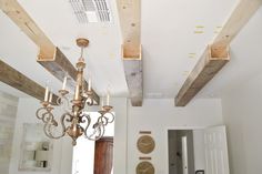 a chandelier hanging from the ceiling in a room with white walls and wooden beams