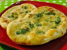 two pizzas sitting on top of a red plate covered in cheese and broccoli