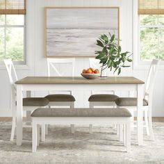 a white table with four chairs and a bowl of fruit on it