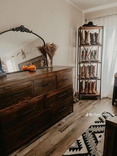 a room with a dresser, mirror and boots on it