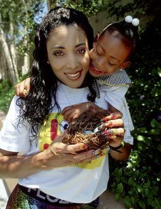 a woman holding a child who is holding a bird nest