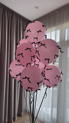 a bunch of pink balloons with birds on them in front of a curtained window