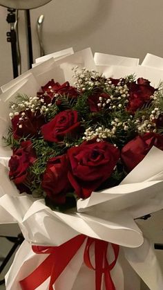 a bouquet of red roses wrapped in white paper