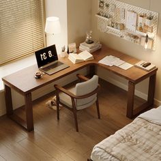 a laptop computer sitting on top of a wooden desk next to a bed in a bedroom