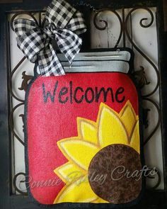 a welcome sign with a sunflower painted on it and a bow hanging from the front door