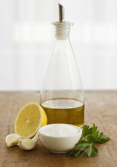 a bottle of olive oil next to garlic and lemon