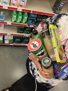 a person holding a bag full of food and drinks in a grocery store with other items on the shelves