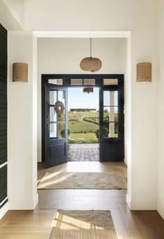 an open door leading into a large room with wood flooring and black glass doors