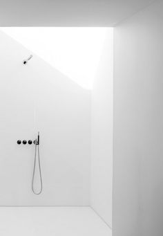 an empty white bathroom with a shower head and hand held shower faucet in the corner