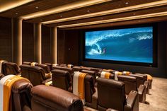 a large screen in the middle of a room with brown leather chairs and yellow striped seats