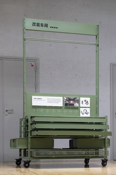 a green cart sitting on top of a hard wood floor next to a wall with writing on it