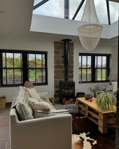 a living room filled with furniture and a chandelier hanging from the ceiling over a fire place